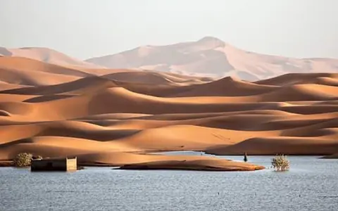 Dunas del Sahara junto a una laguna temporal