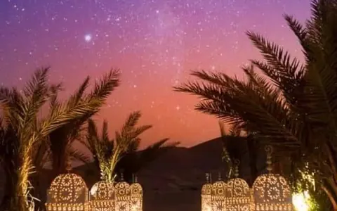 Campamento de lujo en el desierto con faroles y alfombra roja bajo un cielo estrellado