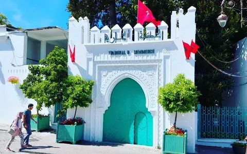 Entrada blanca con puerta turquesa y banderas de Marruecos